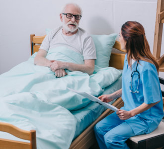 Old man patient and nurse discussing news from newspaper