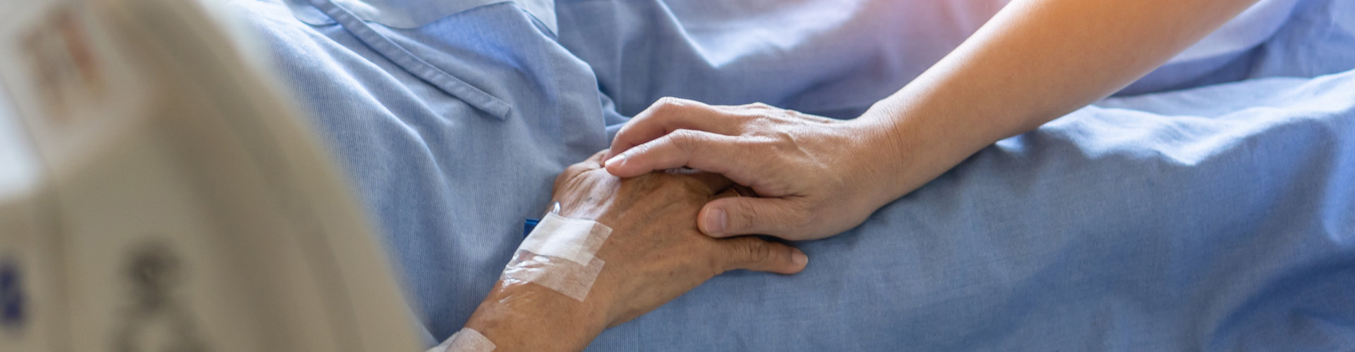 Caregiver holding elderly senior patient (ageing old adult person) hand lying in hospital bed or nursing hospice, geriatrician palliative home, while caretaker having medical health care service