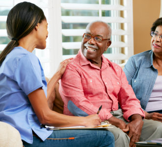 Nurse Making Notes During Home Visit With Senior Couple